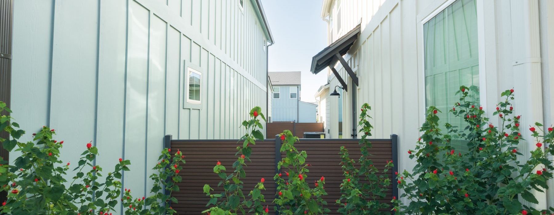 two buildings with a fence and bushes